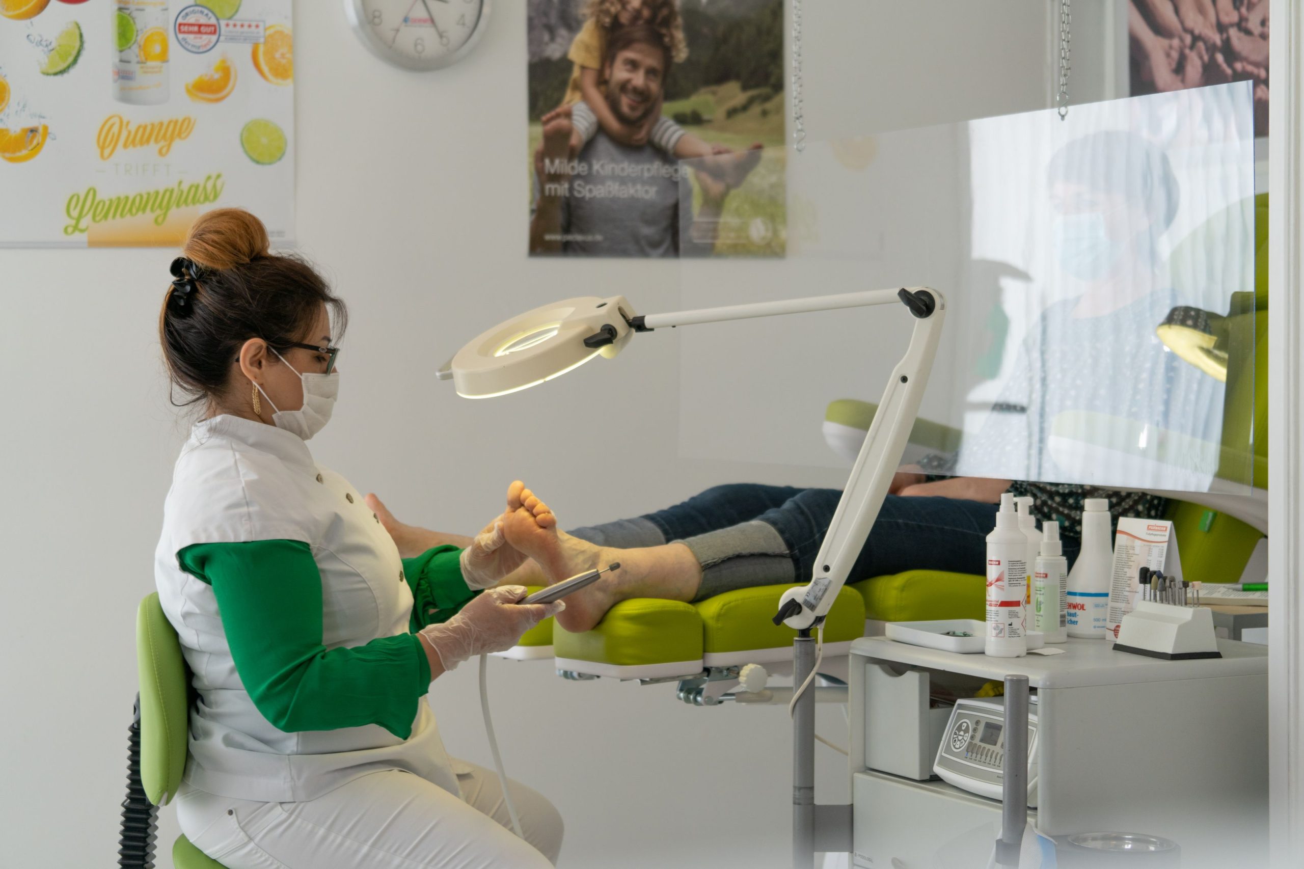Podologin behandelt die Füße eines Patienten in heller, freundlicher Umgebung
